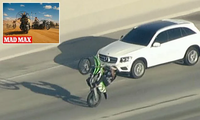 Dystopian Mad Max scene on LA freeway as car thief in stolen SUV is surrounded by huge gang of illegal dirt bikers