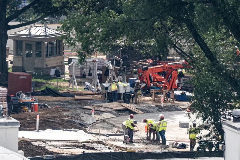 Crews remove the granite seal on the White House helipad, signaling potential project delays