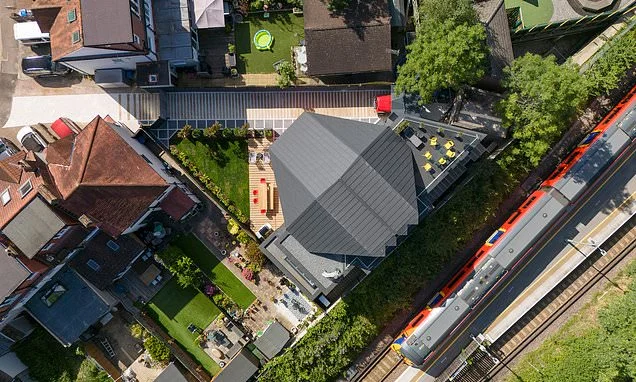 The spaceship in suburbia: Architect's bespoke home overlooking railway lines hides incredible interior but neighbours call it the 'big black batcave'