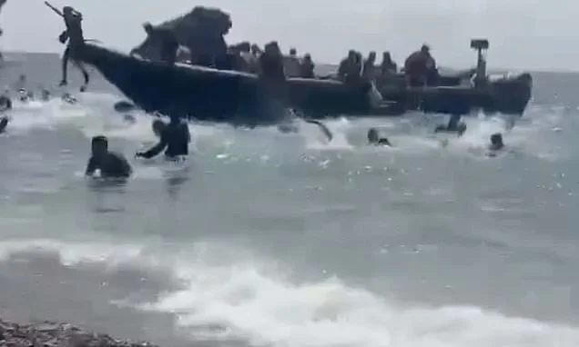 Sunbathers look on in shock as packed migrant boat arrives on Spanish beach and dozens of men run ashore and disappear