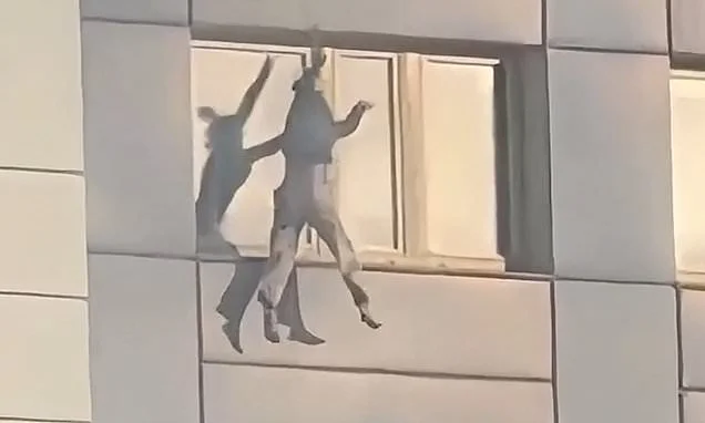 Hair-raising moment woman hangs from 11th floor of burning building before making daring jump to safety